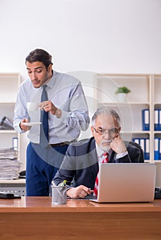 Old boss and young male employee in the office