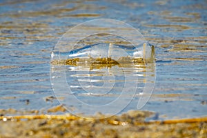 Old bottle floating on the coast, affecting the environment