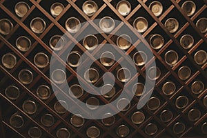 Old bottles of wine on the wall of dark wine cellar. Close-up. Background, pattern, texture. Abstract, design.