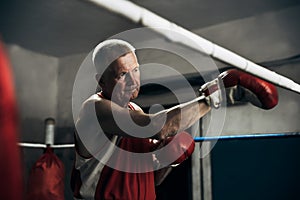 Old boxer practicing her punches at a boxing studio. Close up of a male boxer punching inside a boxing ring