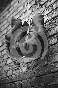Old boxing gloves hang on nail on brick wall with copy space for text. High resolution 3d render