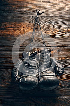 Old boxing gloves hanging on nail on wooden wall.