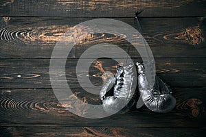 Old boxing gloves hanging on nail on wooden wall with copy space for tex