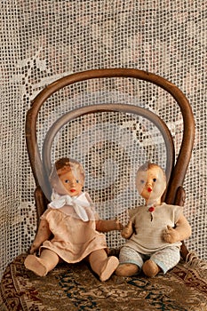 Old boy and girl dolls on an old chair with a lace