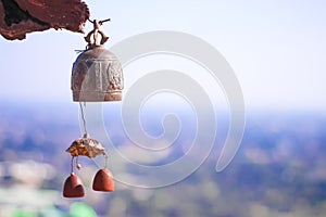 Old brass bell hanging on blurred city and sky background