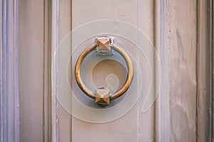 Old brass door knocker on a gray front door