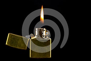 Old Brass Lighter and Flame on a Black Background