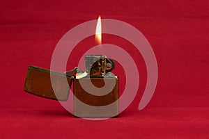 Old Brass Lighter and Flame on a Red Background
