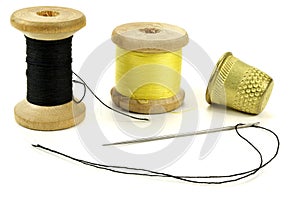 Old brass thimbles, coil with threads and a needle for sewing on a white background