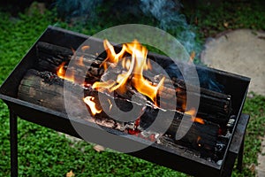 Old brazier with burning firewood on the backyard