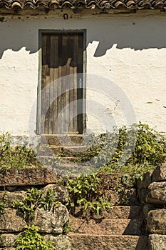 Old brazilian farm house with wooden door stone steps bushes