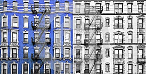 Old brick apartment buildings with fire escapes in New York City in blue black and white