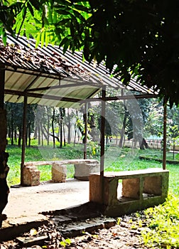 Old brick bench in a park with shade. A gazebo in a garden