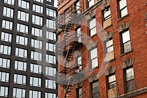 Old Brick Building with Fire Escapes next to a Modern Residential Skyscraper in Tribeca of New York City