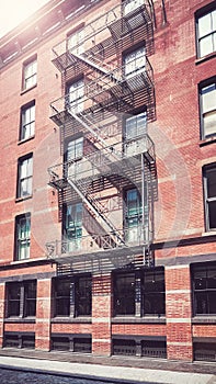 Old brick building with iron fire escape, color toning applied, New York City, USA