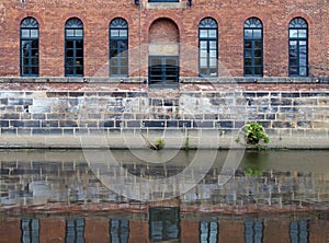 Old brick canal warehouse in leeds with windows reflected in the water