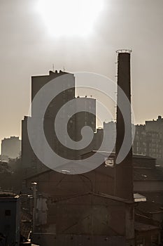 Old brick chimney from an abandoned factory, from the industrial revolution, while an socialist yugoslav housing block building