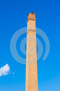 Old brick chimney on the background of clear blue sky