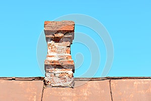 An old brick chimney on a house with an iron roof