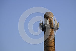 Old brick chimney with mobile phone antennas. Old industrial masonry chimneys