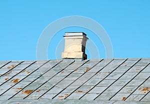 Old brick chimney on the roof of the house.