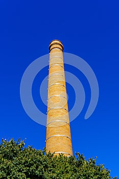 Old brick factory chimney over blue sky
