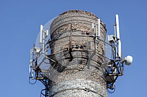 An old brick factory chimney with various antennas