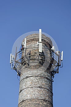 An old brick factory chimney with various antennas