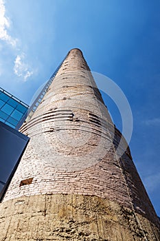 Old brick factory pipe against blue sky.