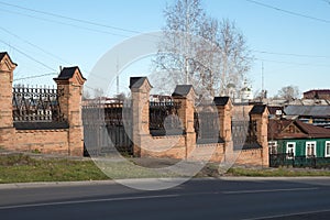 The old brick fence of the city hospital 1898 against the backdrop of the city of Yeniseysk. Krasnoyarsk region. Russia