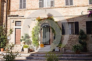 An old brick house of a medieval italian village with ornamental plants and flowers in the court yard Italy, Europe