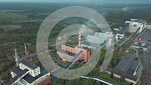 Old brick industrial buildings with tall chimney stack surrounded by forest. Aerial view from above.