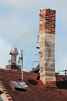 Old brick smokestack on a rooftop with a metal ladder for servicing