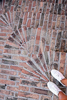 Old brick steps, top view, feet in white sneakers, hiking, streets of the old city