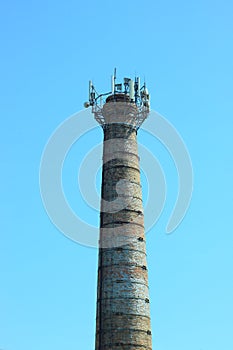 Old brick tower against the clear blue sky background. Belfry for telecommunications. High pipe boiler house