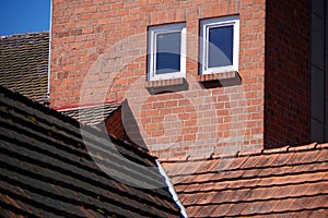 Old brick wall with 2 windows and different tile roofs