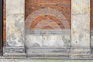 Old brick wall with aged whitewashed pillars on the side of a street