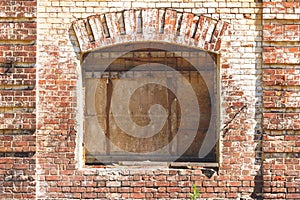 Old brick wall with boarded up window. Old warehouse, retro city architecture. Brickwork of destroyed and weathered bricks with