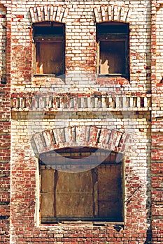 Old brick wall with boarded up windows. Old warehouse, retro city architecture. Brickwork of destroyed and weathered bricks with