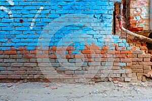 Old brick wall half painted in bright blue color