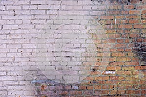 An old brick wall made of red bricks. Part of the wall is painted with a pale pink paint. Empty background of smooth