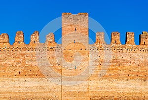 Old brick wall of medieval Italian fortress against the blue sky