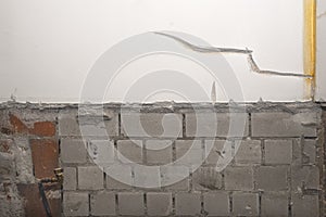 Old brick wall with peeling stucco. Weathered rough wall surface with brickwork