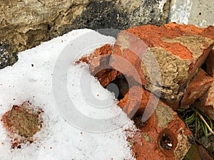 Old brick wall with sharp texture and covered by snow