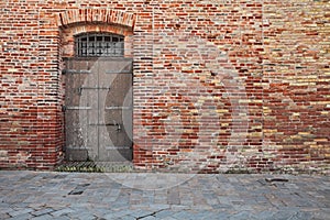 Old brick wall, stone paved sidewalk and ancient wooden door photo