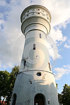 Old brick white ragged water tower on a sunny day