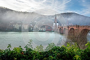 Old Bridge (Alte Brucke) and Neckar river on a foggy day - Heidelberg, Germany photo
