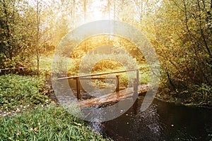Small bridge over river in forest on sunset background