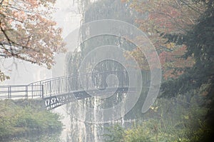 Old bridge in misty autumn park