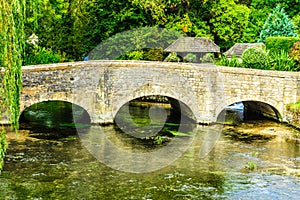 Old bridge over river Coln in village Bibury England photo